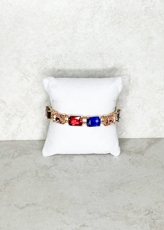 Bracelet with colorful stones on a white cushion against a light gray background