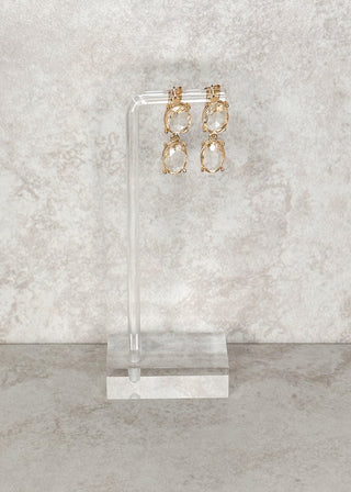 Double oval dangle earrings in champagne displayed on a stand 