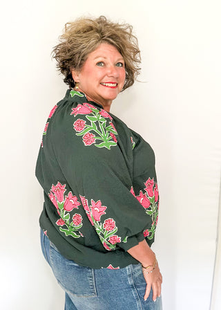 Woman wearing a green blouse with floral embroidered print against a white background