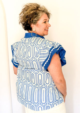 Patterned short-sleeve top in blue with contrast trim with scallops, v-neckline, and relaxed fit.