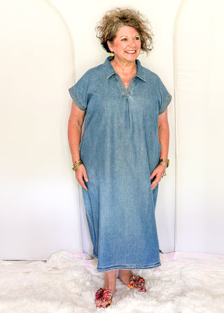 Woman wearing a denim dress standing against a white background