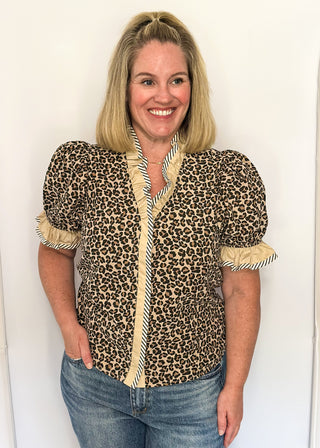 Leopard print blouse with ruffle neckline, puff sleeves, and striped trim.