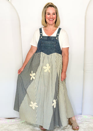 woman modeling a denim overall style dress with gingham floral pattern.