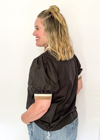 Woman wearing a black blouse with puff sleeves against a white background