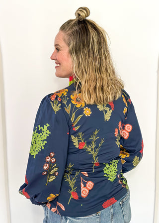 floral long sleeve top with navy background and redish and gold blooms - red and green ruffle around collar and down front - button up