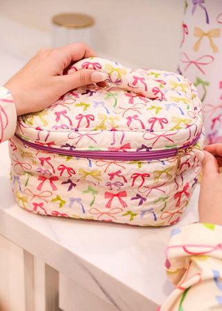 Colorful bow-patterned makeup bag held by a person with a white background