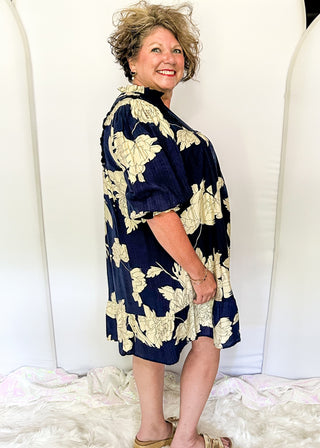 Woman wearing a navy floral dress standing against a white background