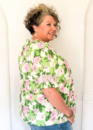 Green and white checkerboard top with pink florals.  v-neck with decorative tassel detail and triple button.