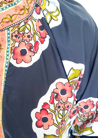 close up of navy maxi dress with colorful floral medallion print, orange embroidered trim at neckline, and smocked cuffs