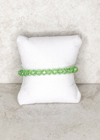 Light green beaded bracelet displayed on a stand 