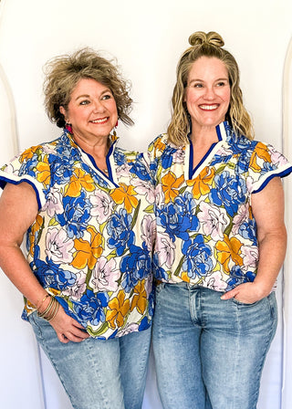 Floral top featuring blue, yellow, and lavender blooms with blue contrast trim on neckline and sleeves.
