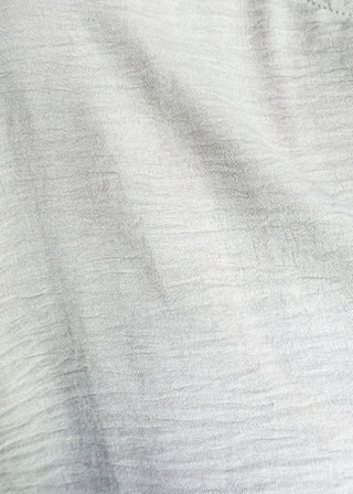 Close up of solid textured blouse with a V-notch neckline, short sleeves