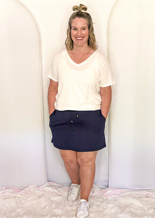 woman wearing navy skort with pockets and white tee.