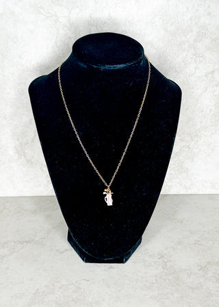 Gold necklace with a golf club bagt pendant on a black velvet bust against a white background