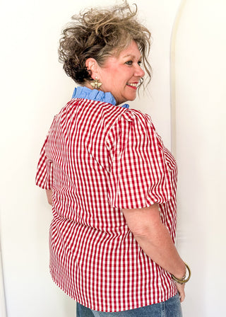 Women’s gingham blouse with decorative buttons and statement neckline detail.