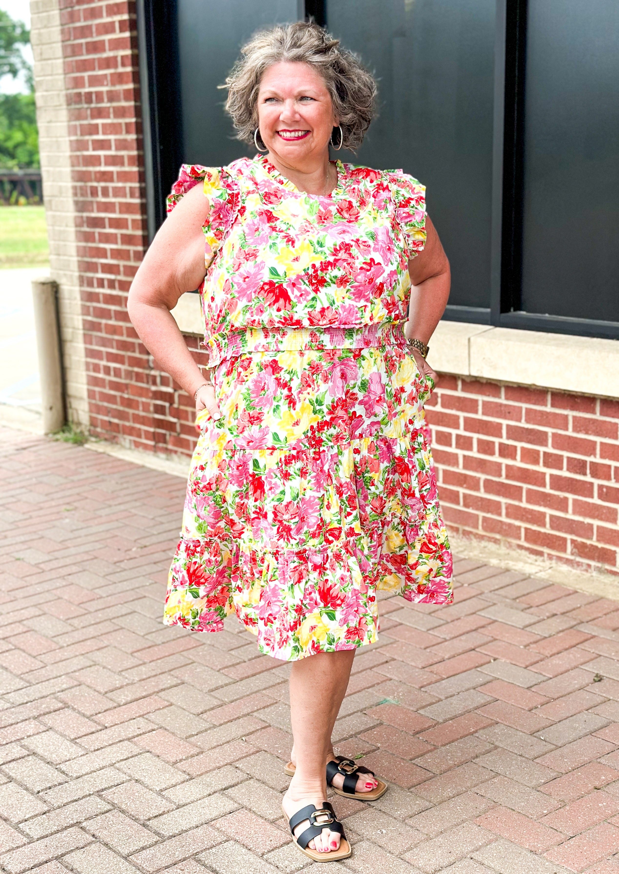 bright floral print smocked waist dress with pockets, ruffle sleeve and neck and one around the bottom  - print colors are yellow, pinks, reds and some green