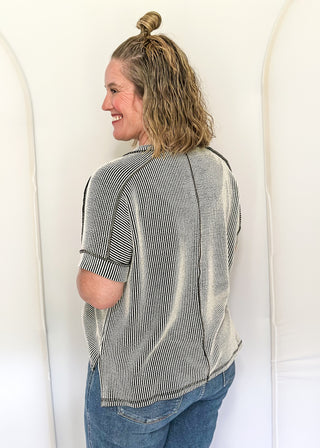 Person wearing a striped shirt and blue jeans standing against a white background