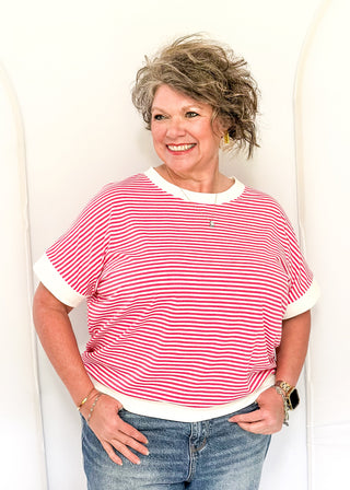 Woman wearing a red and white striped shirt and blue jeans against a white background