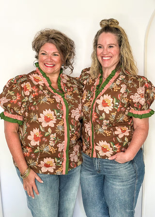 pink and golden botanicals on a brown background.  Short ruffle sleeves, v-neck ruffle collar in pink and green 