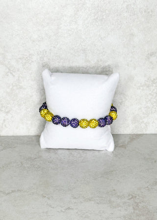 Bracelet with colorful beads on a white pillow against a textured gray background
