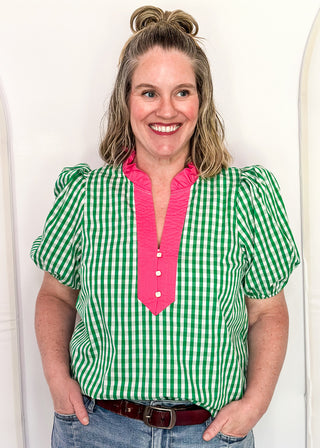 Women’s gingham blouse with decorative buttons and statement neckline detail.