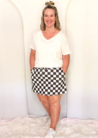 woman wearing checkered skort with built-in shorts with a white tee.