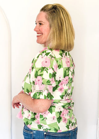 Green and white checkerboard top with pink florals.  v-neck with decorative tassel detail and triple button.