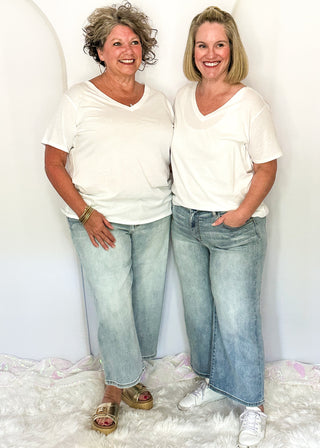 Two women wearing denim crop jeans and white tee.
