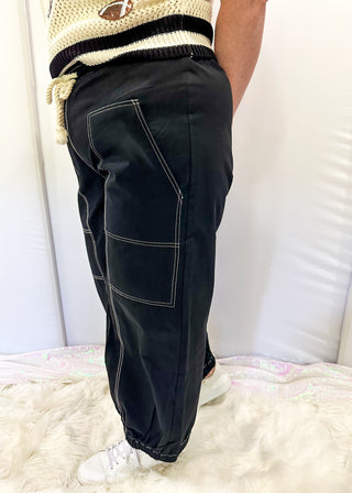 Black balloon style pants with rope drawstring waist. White stitching around pockets and crop cut.