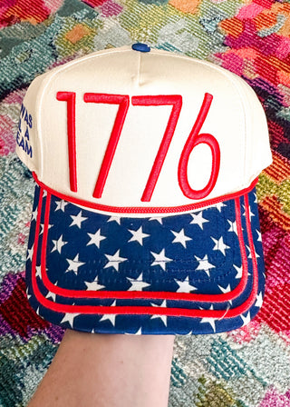 snap back hat with 1776 embroidered in red with blue bill with white stars and red stitching.