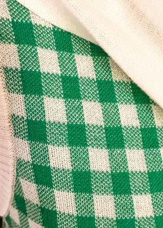 Close up of sleeveless green checkered sweater with faux wrap in cream