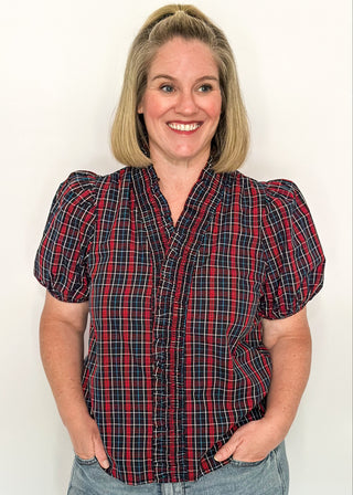 woman wearing a plaid puff sleeve top in dark navy with short sleeves and a V-neckline.