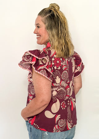 Plum blouse with bold cream and pink florals; flutter sleeves, and striped neckline