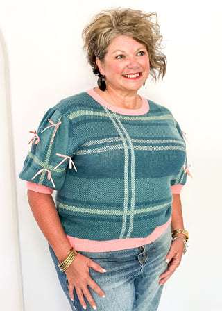 Turquoise plaid short sleeve sweater with pink trim and bow accents on the sleeves