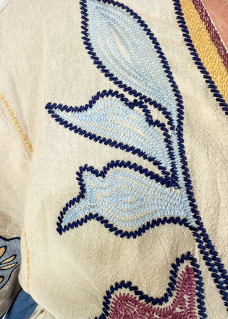 v-neck dress in cream with dusty blue on the side and arm at the edge - large floral print embroidery throughout - above the knee in length