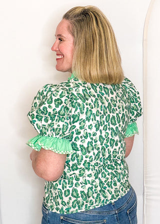 Green animal print blouse with contrast trim, button front, and ruffle sleeves