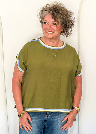 women wearing olive green top with cap sleeves and crew neckline, styled with jeans.