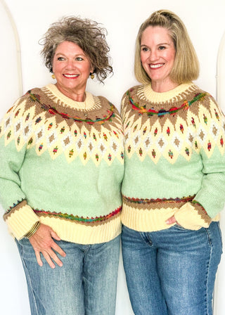 Two women modeling a cozy long sleeve sweater with geometric pops of color with a cream and light blue base