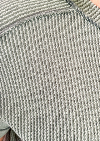 Close-up of a textured green fabric with a visible seam.