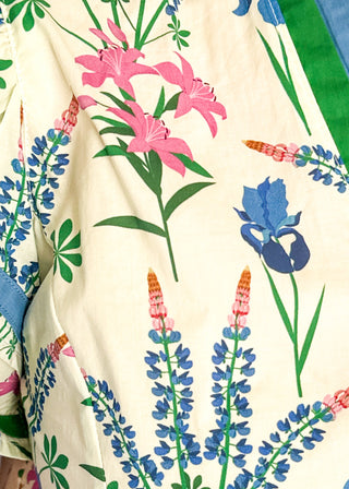 Cream short sleeve floral top with blue, pink, and green flowers, featuring a split V-neckline with green trim and a relaxed fit.