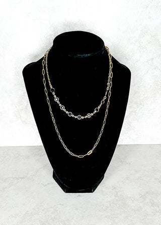 Double chain with black stones on one necklace on a black bust against a white background