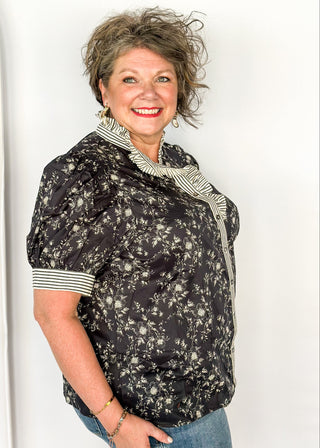 Black with small white florals-short sleeve button up top. Black and white stripe ruffle collar and sleeve binding.  