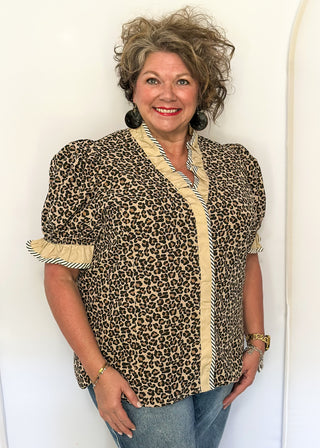 Leopard print blouse with ruffle neckline, puff sleeves, and striped trim.