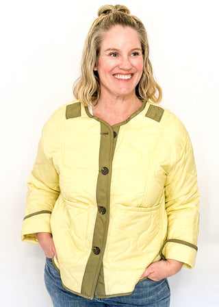 Light sage green quilted jacket with darker contrast trim, long sleeves, patch pockets, and button-front closure