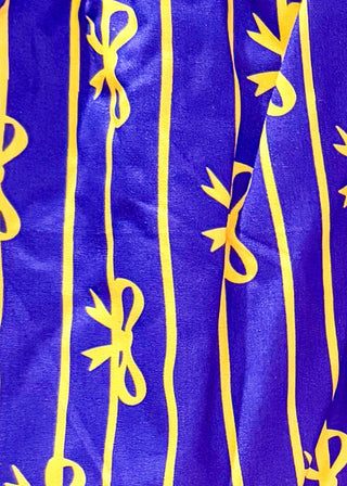 Purple boxer shorts with pockets. Gold stripe pattern with bows throughout. Elastic waist. 