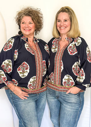 Navy boho print top featuring smocked collar large floral bundles and colorful border trim.
