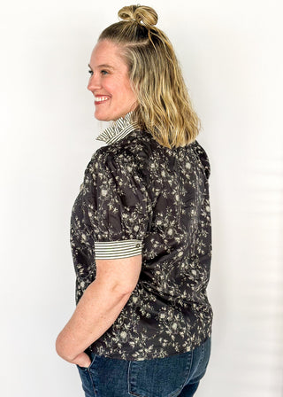 Black with small white florals-short sleeve button up top. Black and white stripe ruffle collar and sleeve binding.  