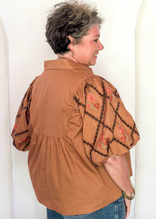woman in chestnut poplin puff sleeve top with embroidery. 