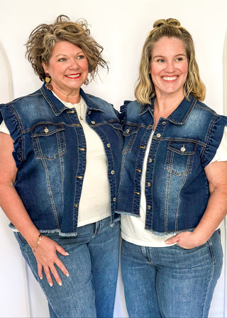 Sleeveless medium-wash denim button-up vest featuring ruffled shoulders, front button closure, chest pockets, and a raw hem 