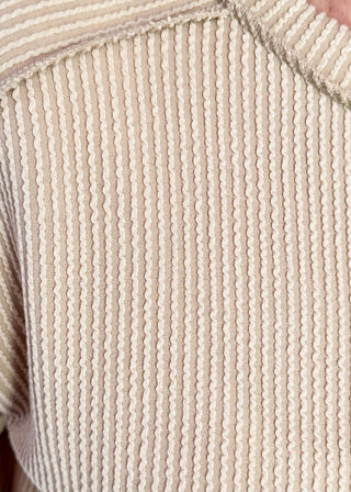 Close-up of a textured beige fabric with a ribbed pattern.